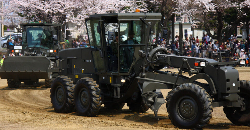 自衛隊の車が桜の近くを走る写真