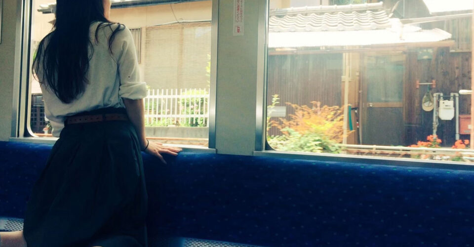 電車の中から外を眺める女性