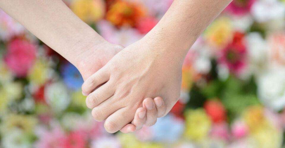 花の前で手を繋いでいる写真